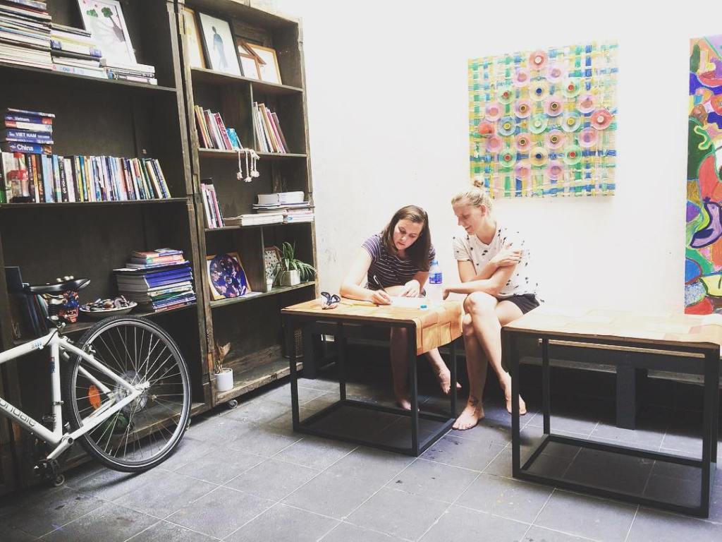 Two foreigners write on a piece of paper in a house in Vietnam.