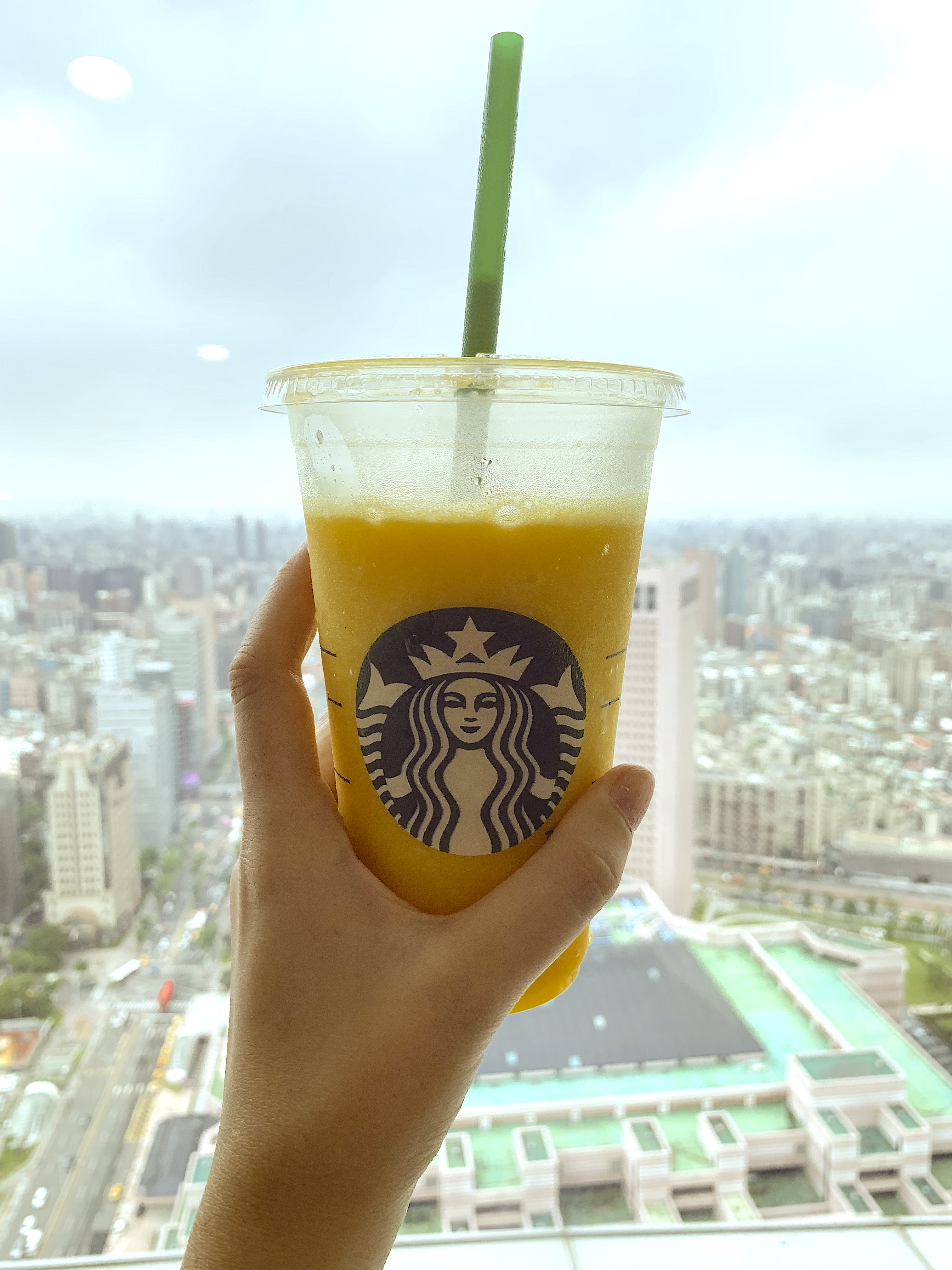 Hand-holds-Starbucks-cup-in-front-of-city-view
