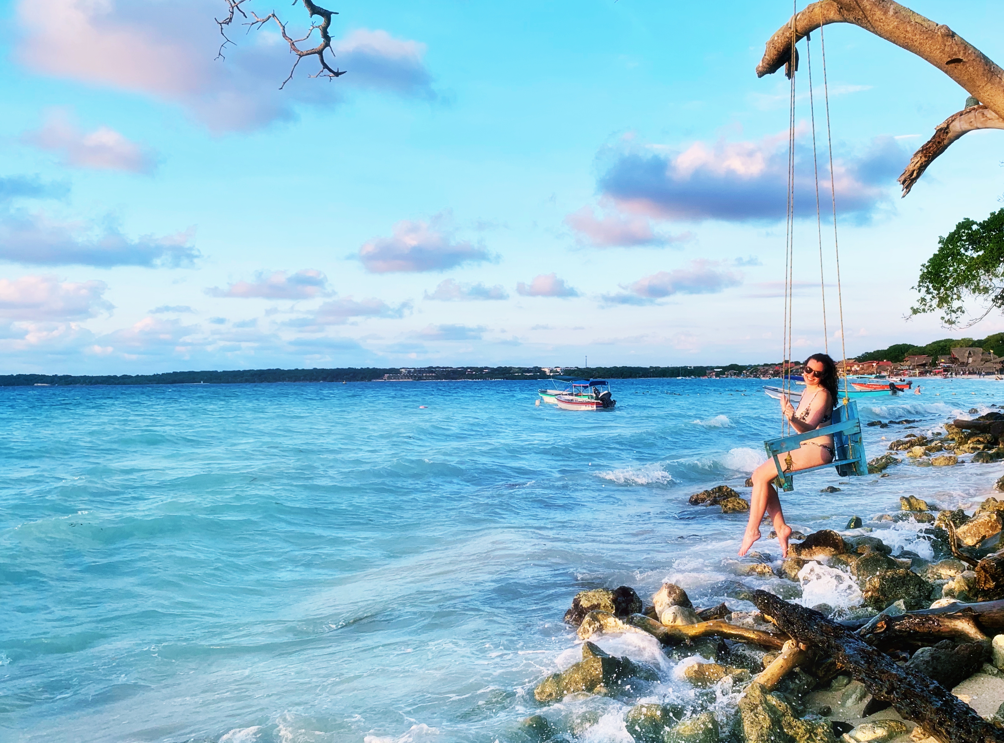 A girl swings on over the water in Playa Blanca, Colombia