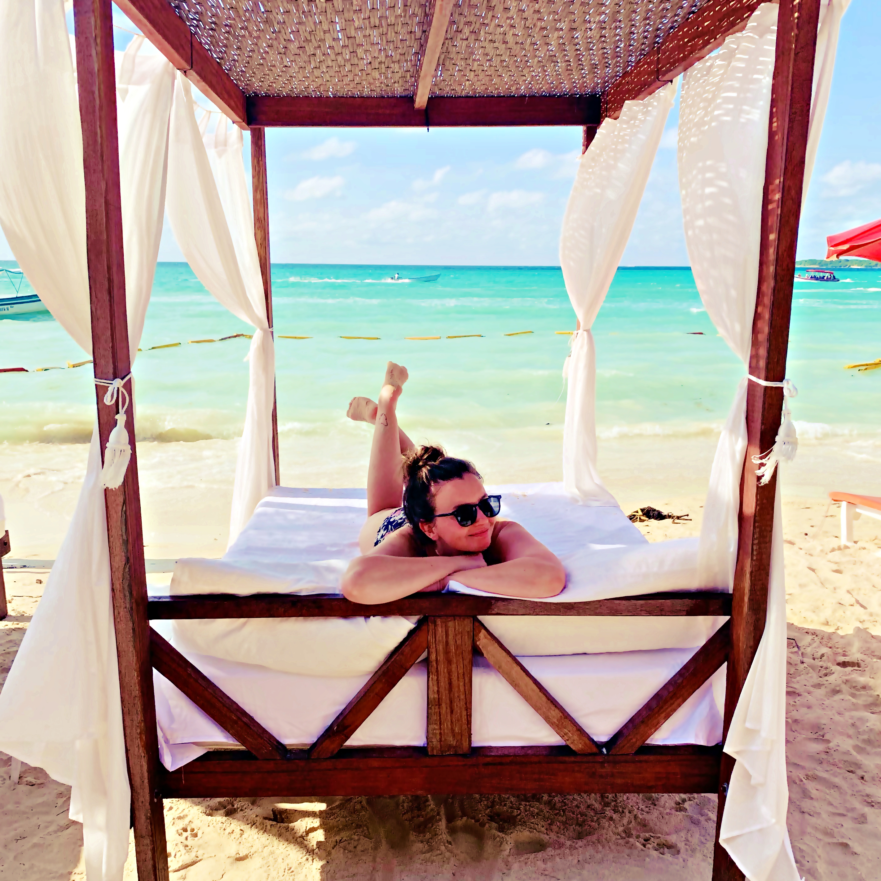 A girl lounges on a cabana in Playa Blanca, Colombia, with the water behind her